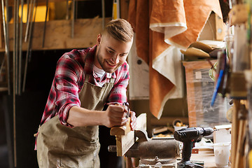 Image showing carpenter working with plane and wood at workshop