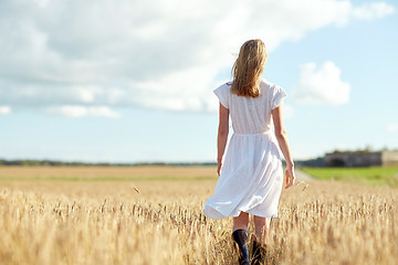 Image showing young woman in white dress walking along on field