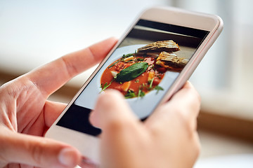 Image showing hands with gazpacho soup photo on smartphone at restaurant