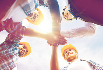 Image showing close up of builders in hardhats with hands on top