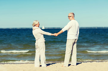 Image showing happy senior couple holding hands on summer beach