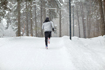 Image showing man running on snow covered winter road in forest