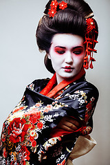 Image showing young pretty geisha in black kimono among sakura, asian ethno