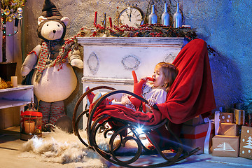 Image showing Little girl and rocking chair near fireplace