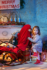 Image showing Little girl and rocking chair near fireplace