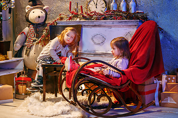 Image showing Little girls and rocking chair near fireplace