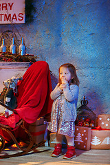 Image showing Little girl and rocking chair near fireplace