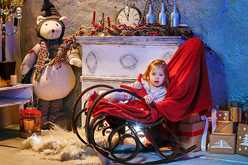 Image showing Little girl and rocking chair near fireplace