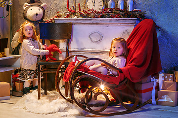 Image showing Little girls and rocking chair near fireplace