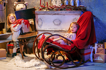 Image showing Little girls and rocking chair near fireplace