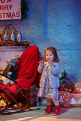 Image showing Little girl and rocking chair near fireplace