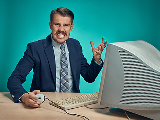 Image showing Angry businessman using a monitor against blue background