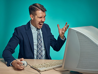 Image showing Angry businessman using a monitor against blue background