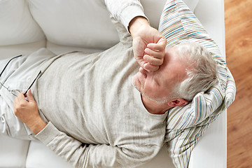 Image showing close up of tired senior man lying on sofa at home