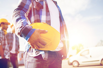 Image showing close up of builder holding hardhat at building