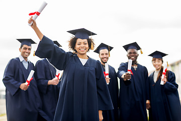 Image showing happy students in mortar boards with diplomas