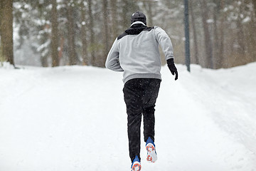 Image showing man running on snow covered winter road in forest