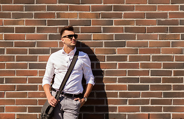 Image showing young man in sunglasses with bag over brickwall