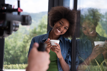 Image showing African American woman drinking coffee looking out the window