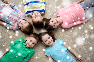 Image showing happy smiling children lying on floor over snow