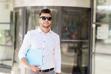 Image showing young man with business file on city street