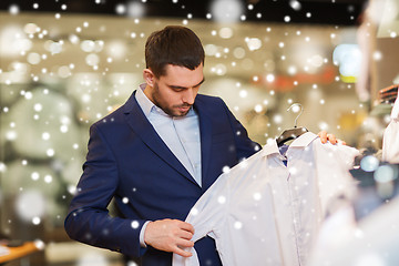 Image showing happy young man choosing clothes in clothing store