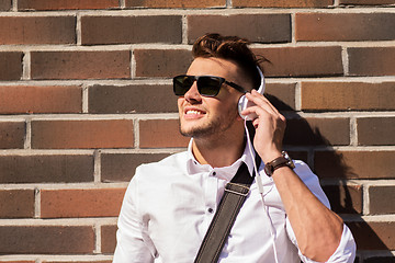 Image showing young man in headphones over brickwall