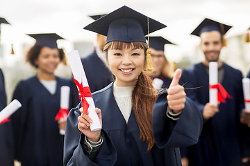 Image showing happy students with diplomas showing thumbs up