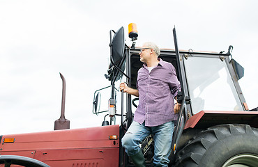 Image showing old man or farmer getting out of tractor at farm