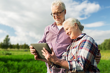 Image showing happy senior couple with tablet pc at summer farm