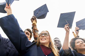 Image showing happy students or bachelors waving mortar boards