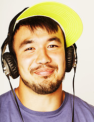 Image showing young asian man in hat and headphones listening music on white b