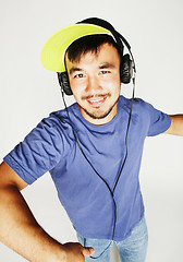 Image showing young asian man in hat and headphones listening music on white b