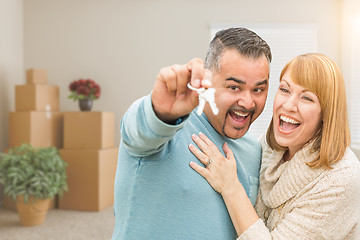 Image showing Couple Holding House Keys Inside Empty Room with Moving Boxes