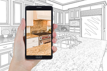 Image showing Hand Holding Smart Phone Displaying Photo of Kitchen Drawing Beh