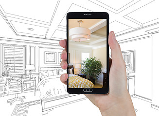 Image showing Hand Holding Smart Phone Displaying Photo of Bedroom Drawing Beh