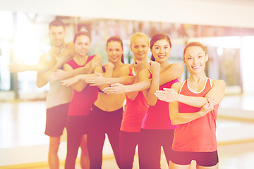 Image showing group of smiling people stretching in the gym