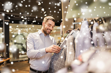 Image showing happy young man choosing clothes in clothing store