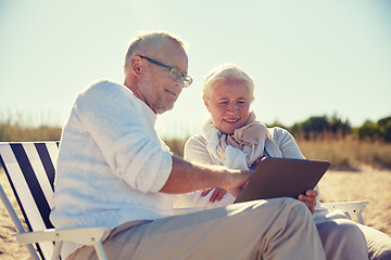 Image showing happy senior couple with tablet pc on summer beach