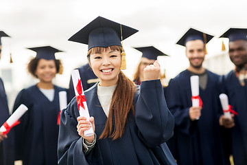 Image showing happy students in mortar boards with diplomas