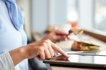 Image showing woman with tablet pc and panini sandwich at cafe