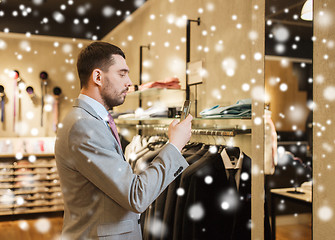 Image showing man in suit with smartphone at clothing store
