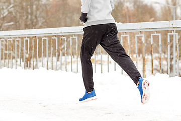 Image showing man running along snow covered winter bridge road