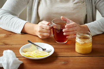 Image showing close up of woman adding lemon to tea cup