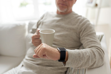 Image showing close up of old man with mug looking at wristwatch