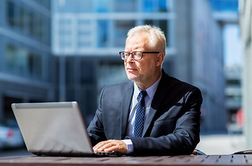 Image showing senior businessman with laptop at city street cafe