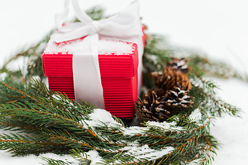 Image showing christmas gift and fir wreath with cones on snow