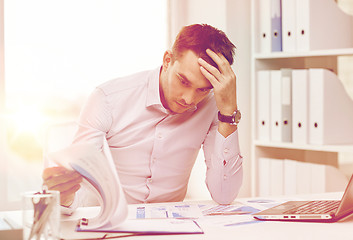 Image showing stressed businessman with papers at office