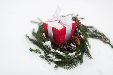 Image showing christmas gift and fir wreath with cones on snow