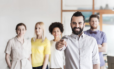 Image showing happy man pointing finger at you over office team